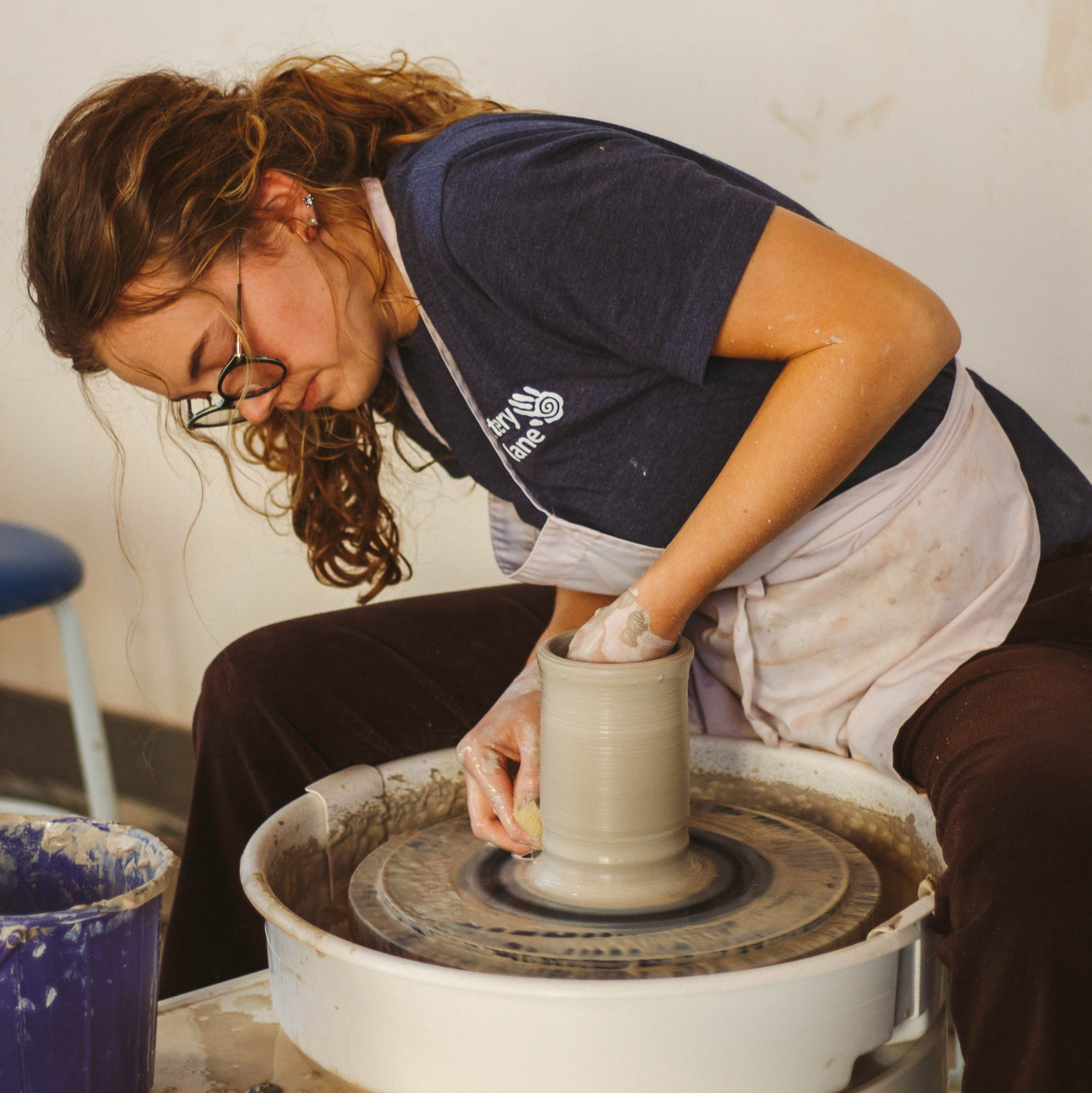 Girl spinning clay on pottery wheel